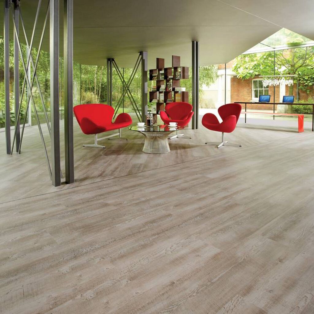Three red chairs and a round table placed upon a Commercial Luxury Vinyl Flooring